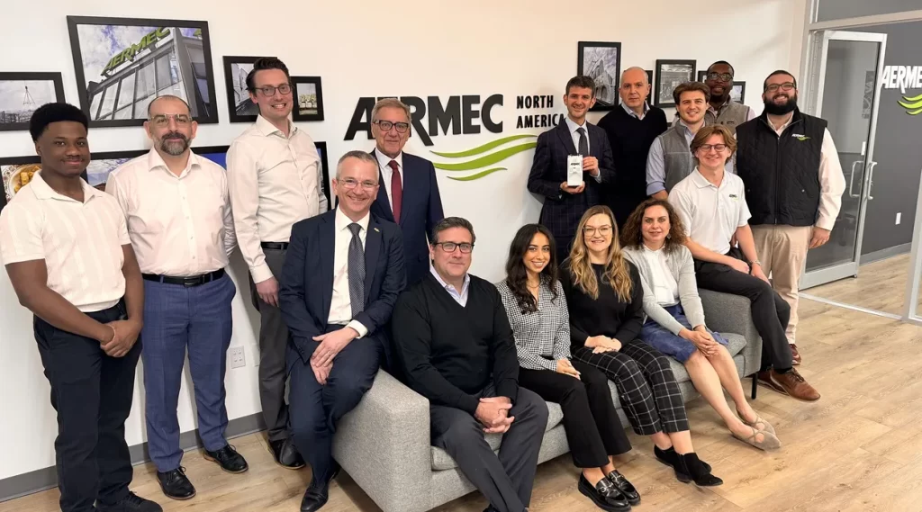 Group of diverse professionals posing for a team photo in an AERMEC North America office, smiling at the camera.
